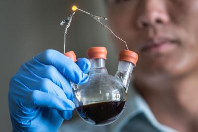 SLAC/Stanford's Yi Cui holds a lab demonstration of his group's new lithium-polysulfide flow battery contained in a simple flask. The design could serve as a model for a low-cost, long-life battery that enables solar and wind energy to become major suppliers to the electrical grid. Credit: Matt Beardsley, SLAC National Accelerator Laboratory 