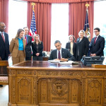 President Barack Obama signs copies of the fiscal year 2015 budget as Office of Management and Budget staff look on in the Oval Office. Photo credit: Pete Souza/Official White House Photo